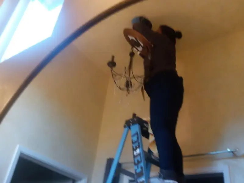 Electrician installing a chandelier in a Trenton residence